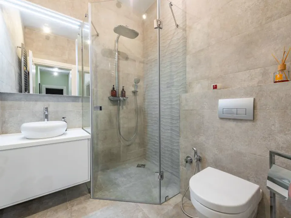 Een witte badkamer met inloopdouche achter glas, hangtoilet en wastafel