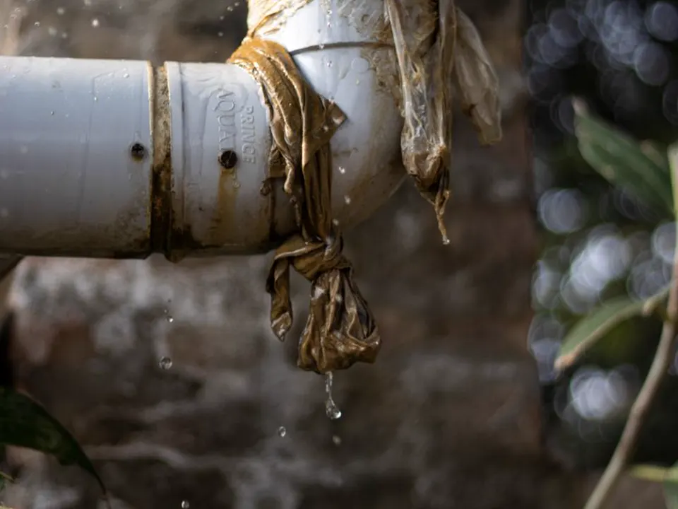 Water lekt uit een kapotte buis die met een natte doek is omwikkeld