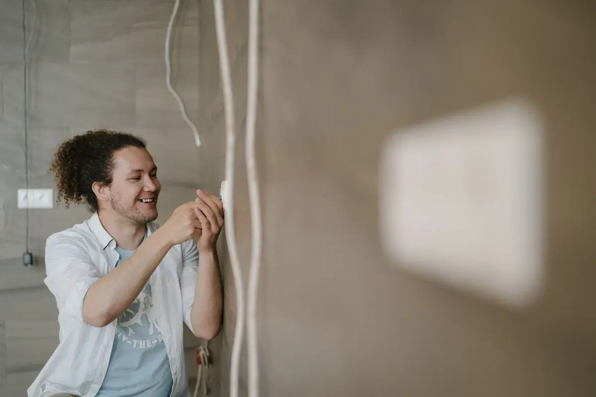 Elektricien sluit lachend bedrading aan op een muur