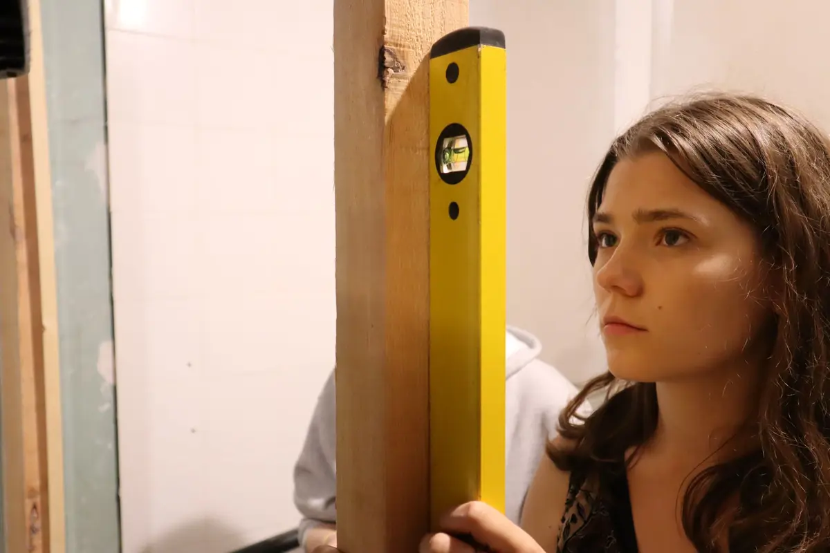 Vakvrouw houdt een waterpas tegen een kozijn