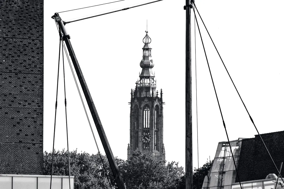 De Onze Lieve Vrouwetoren van Amersfoort tussen twee scheepsmasten, in zwart-wit
