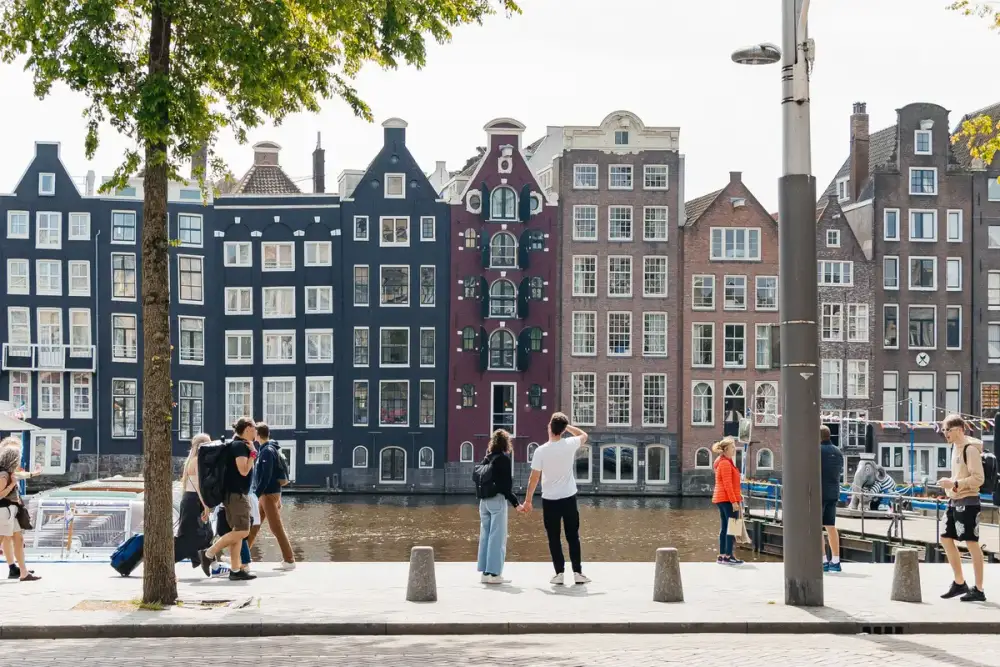 Grachtenpanden aan het Damrak in Amsterdam, met mensen op de kade